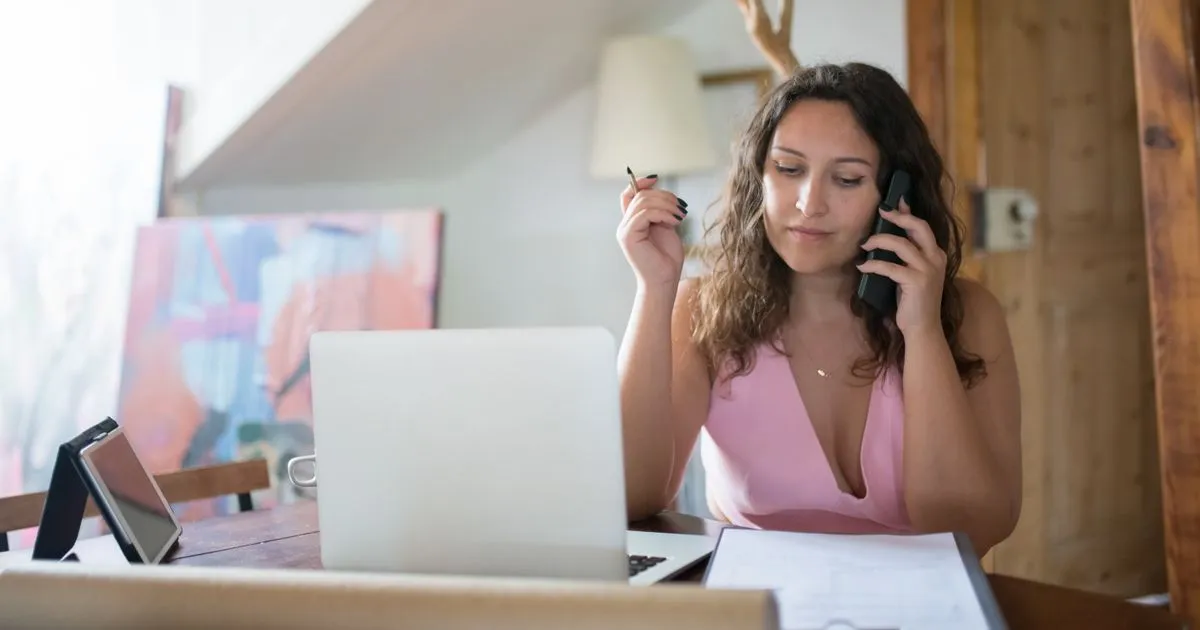 Woman at her home desk calling for debt help in Canada with paperwork ready