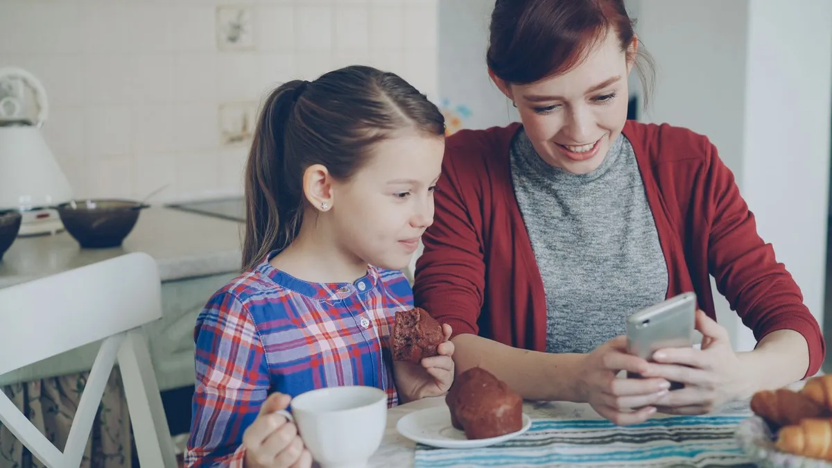 Parent on the phone in the kitchen arranging debt help on benefits with a licensed professional