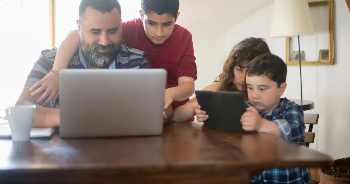 Family at their kitchen table using a laptop to look into debt help on benefits in Canada