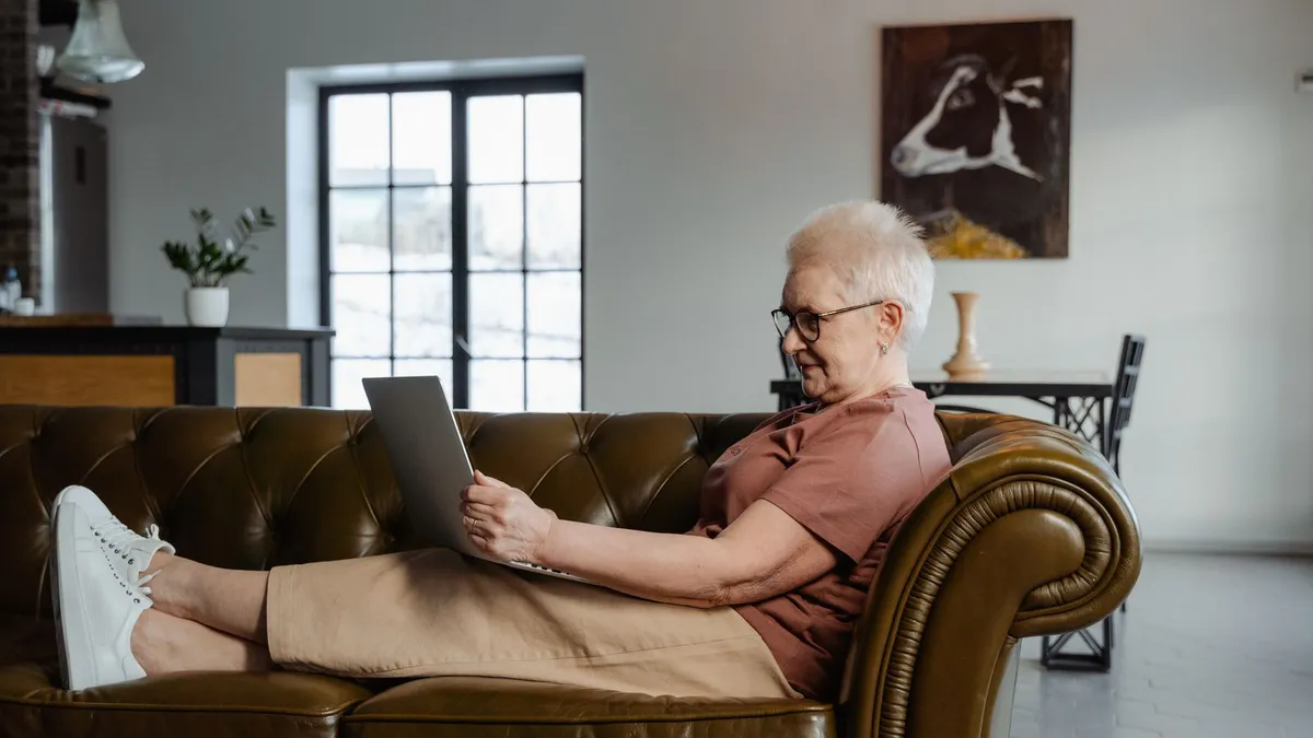 Retired woman using a laptop at home to compare debt help for seniors options