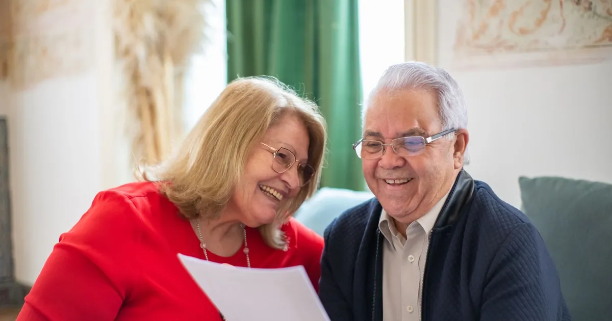 Senior couple reviewing documents at their kitchen table while looking into debt help for seniors in Canada