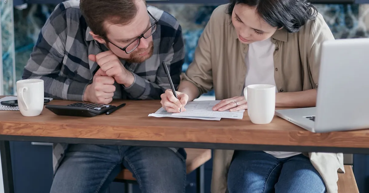 Person budgeting at a kitchen table with bills and a notebook while looking into low income debt help in Canada